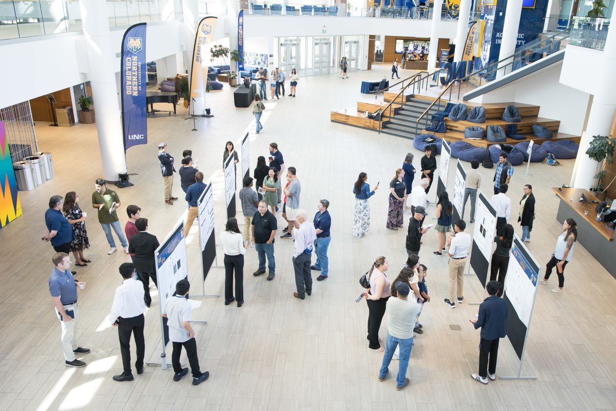 a large crowd gathers around research posters