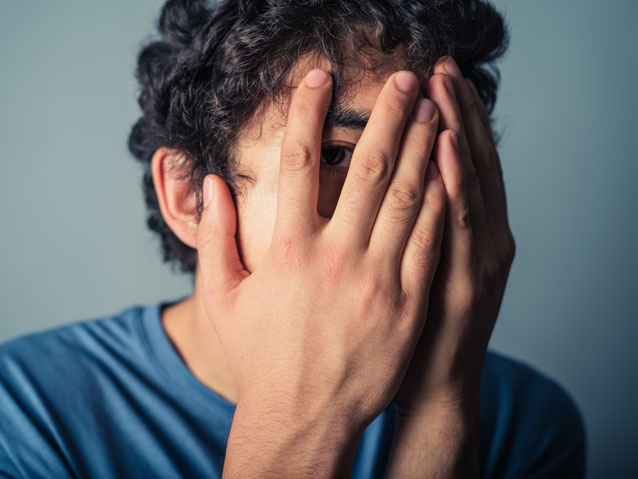 Student peeking nervously through fingers