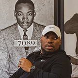 Rico Wint '08 sits in front of a photo of Martin Luther King Jr.