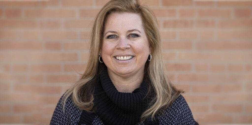 Jessica May standing against a brick wall smiling