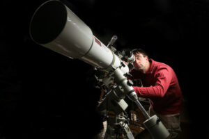 Professor Charles Kuehn, observes a telescope.