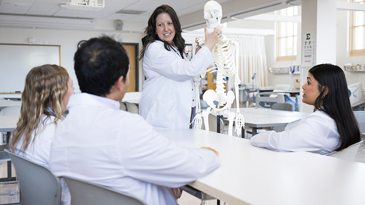 A osteopathic medical student holding a skeleton model.