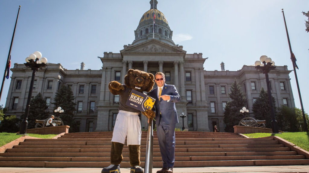 Andy standing with Klawz, UNC's mascot, on the steps of the capitol building.