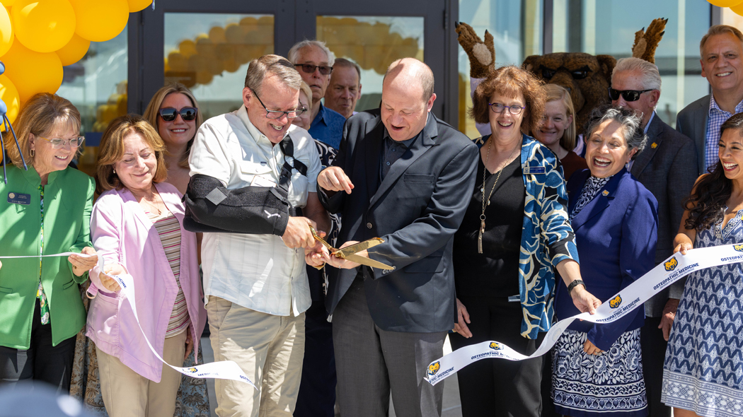 President Andy Feinstein standing with Colorado Governor Jared Polis and other university leaders cutting the ribbon in front of the new college.