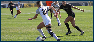 women's soccer athlete kicking the ball down the field.