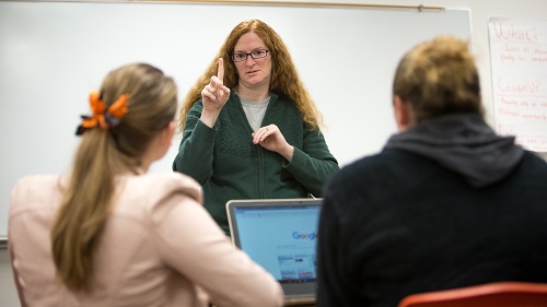 Deaf person instructing students in ASL.