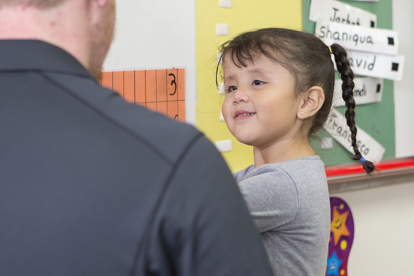 Young girl looking at an adult male in the classroom. 