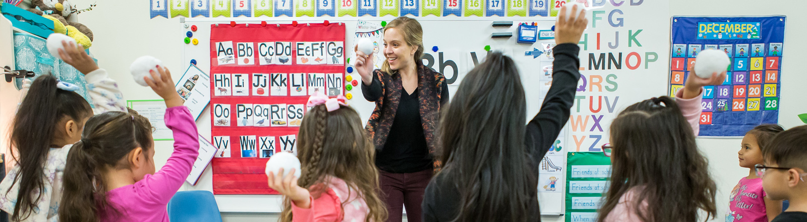 A teacher leads a project with her elementary school students in a classroom.