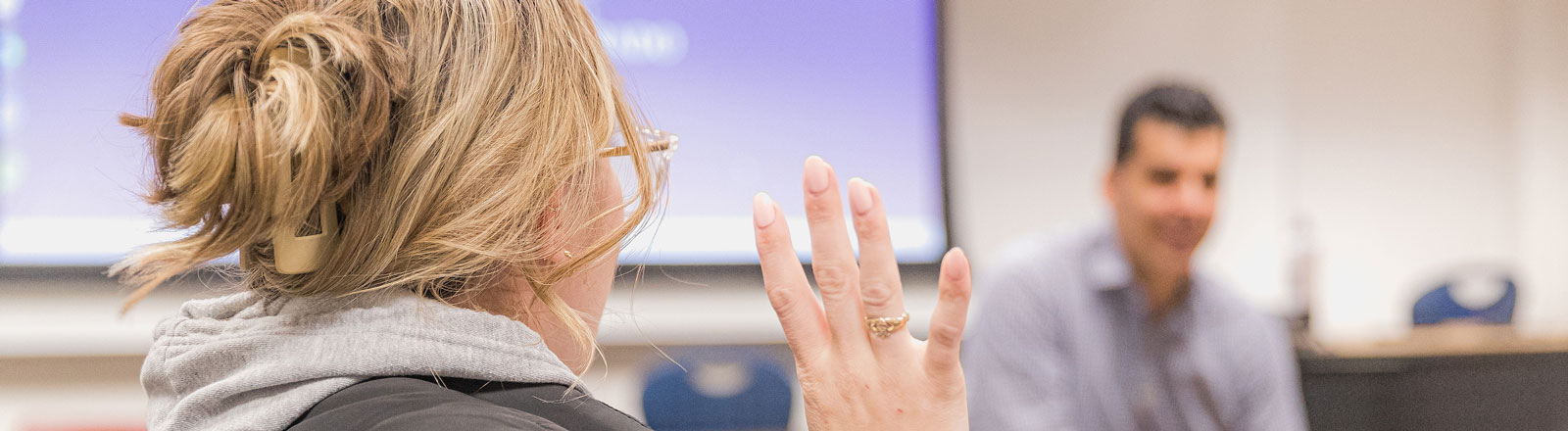 Student raising a hand to answer a question in class.