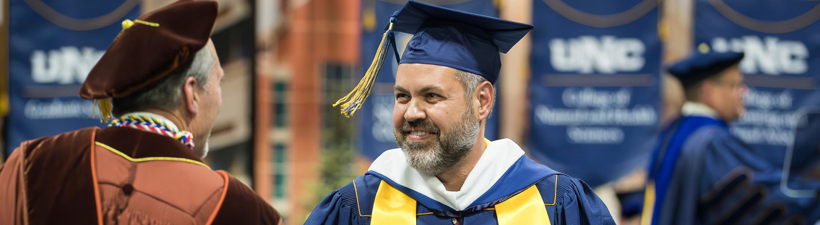 Male graduate student receiving congratulations at commencement ceremony.