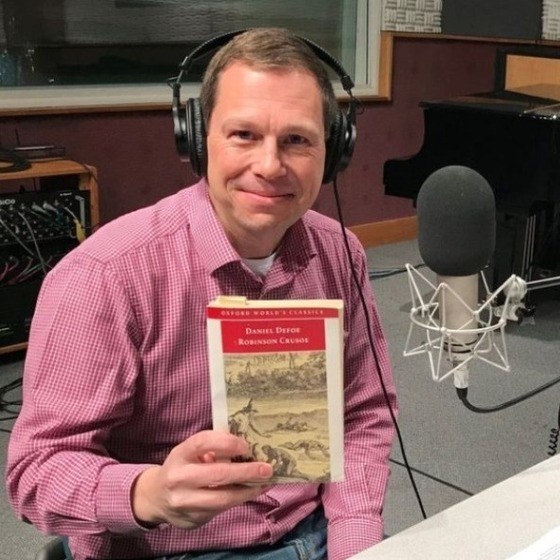 Andreas Mueller holding a copy of "Robinson Crusoe" while in the recording studio for an episode of BBC's "The Forum."