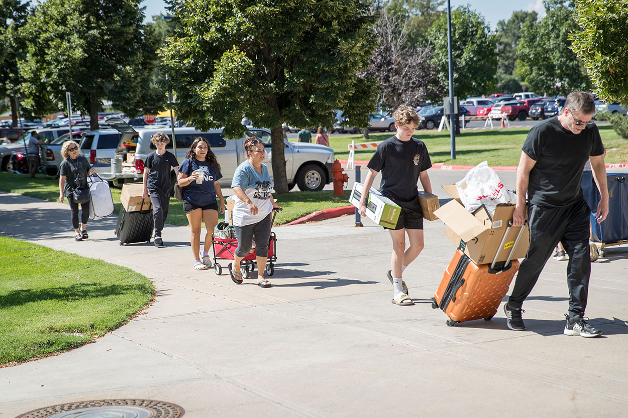 Line of people carrying luggage on the street moving into campus.