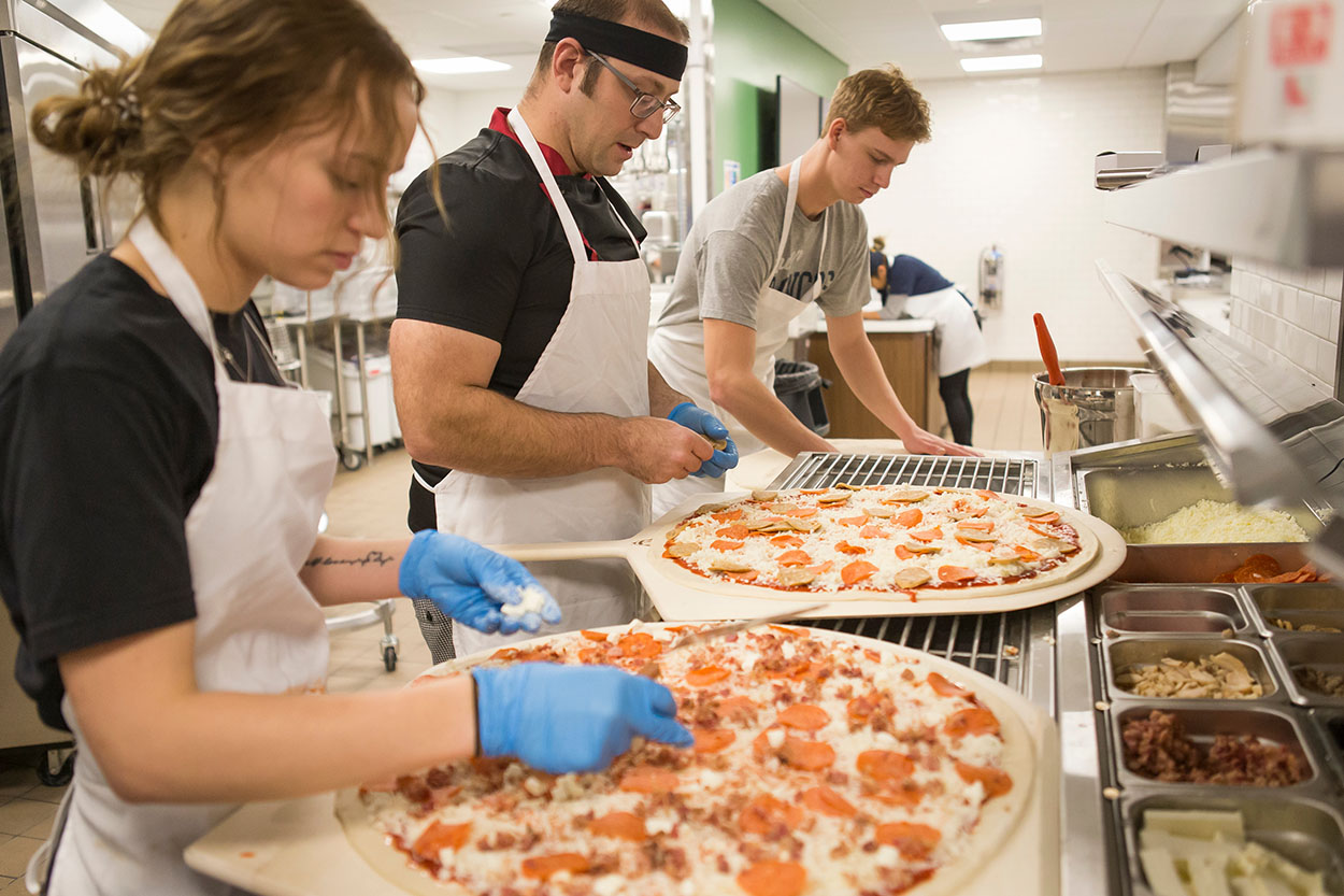 Students making pizza in the school kitchen.