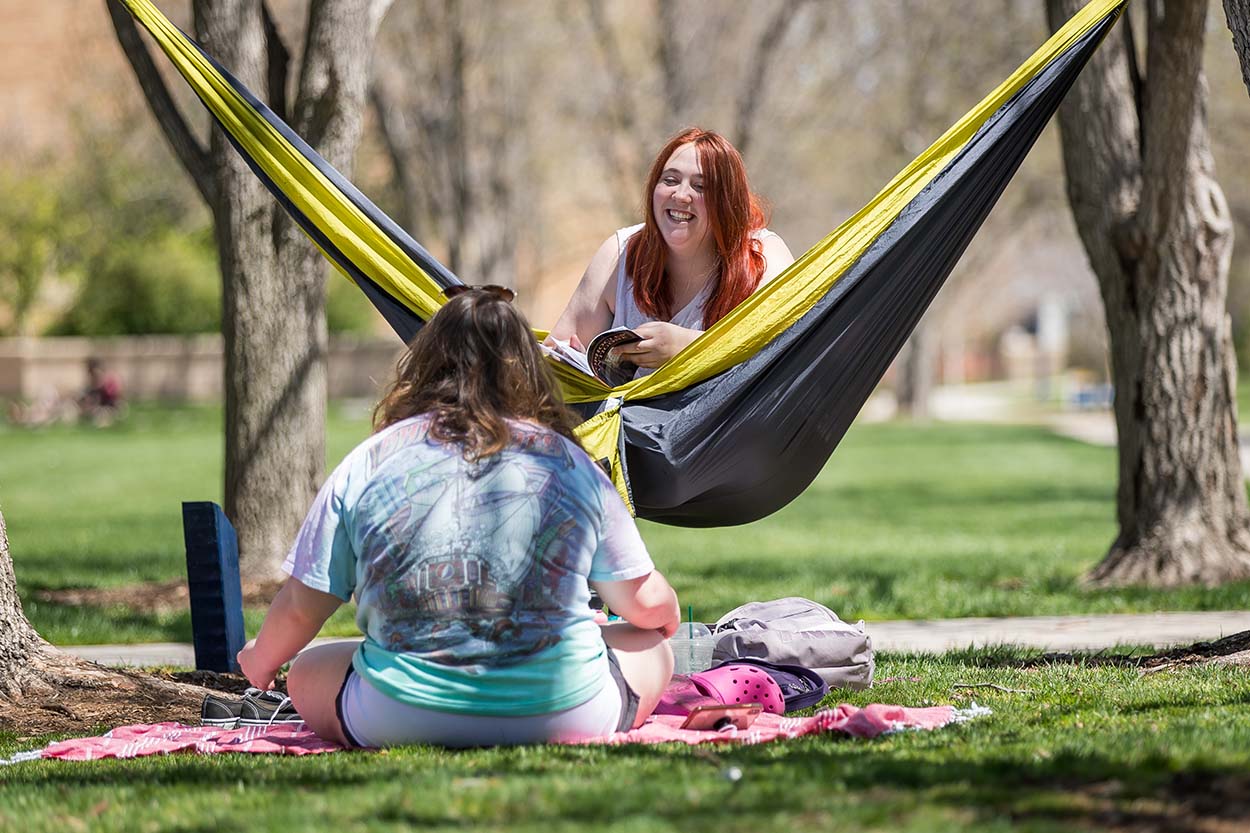 Student sit in a hammock on campus.