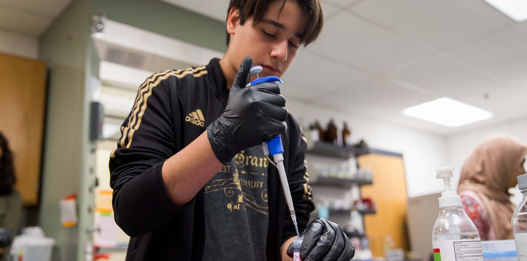 A Frontiers of Science Institute student titrates a solution into a test tube.