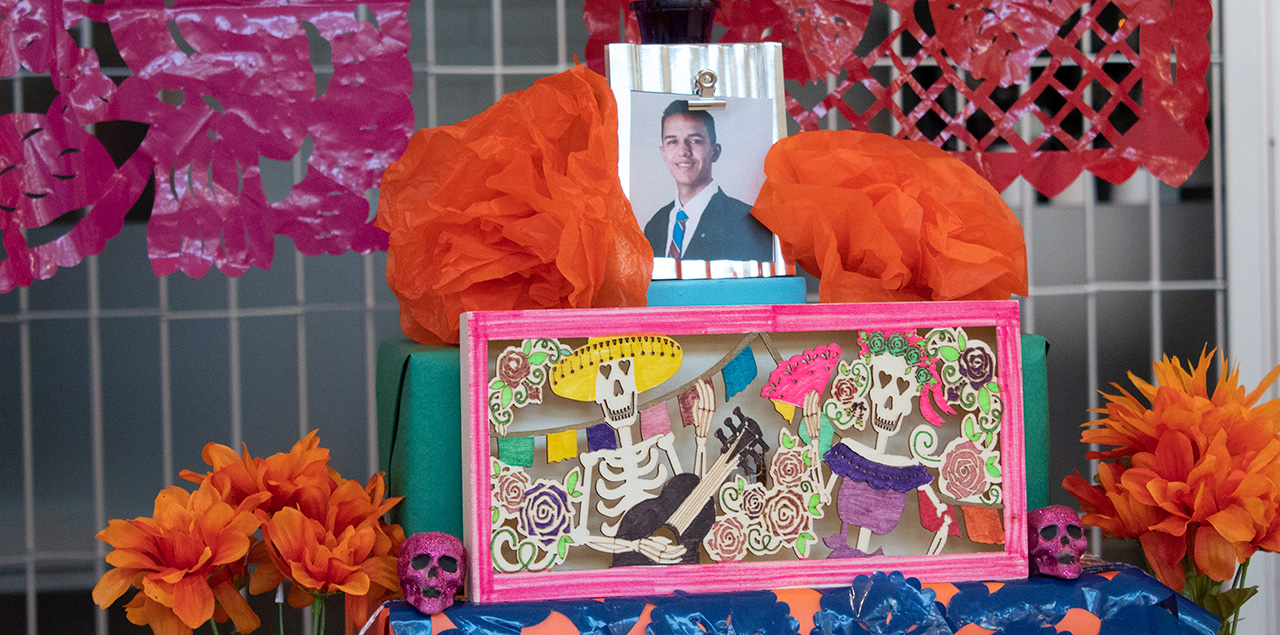 Bright Day of the Dead altar with pictures, candles and decorations on it.