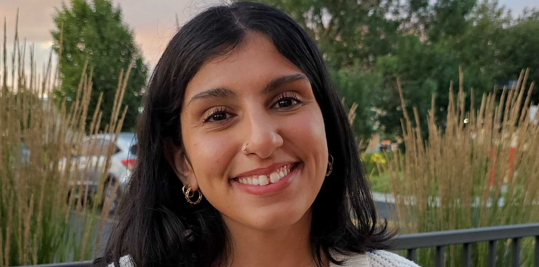 Yasmeen Mustafa smiles in front of a sunset.