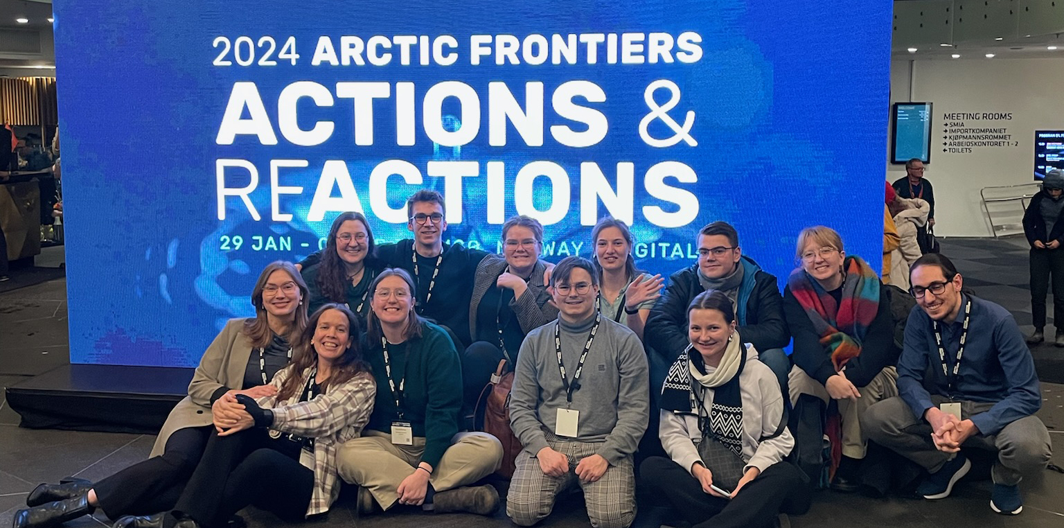 Group of students sitting on the floor in front of Arctic Frontiers sign