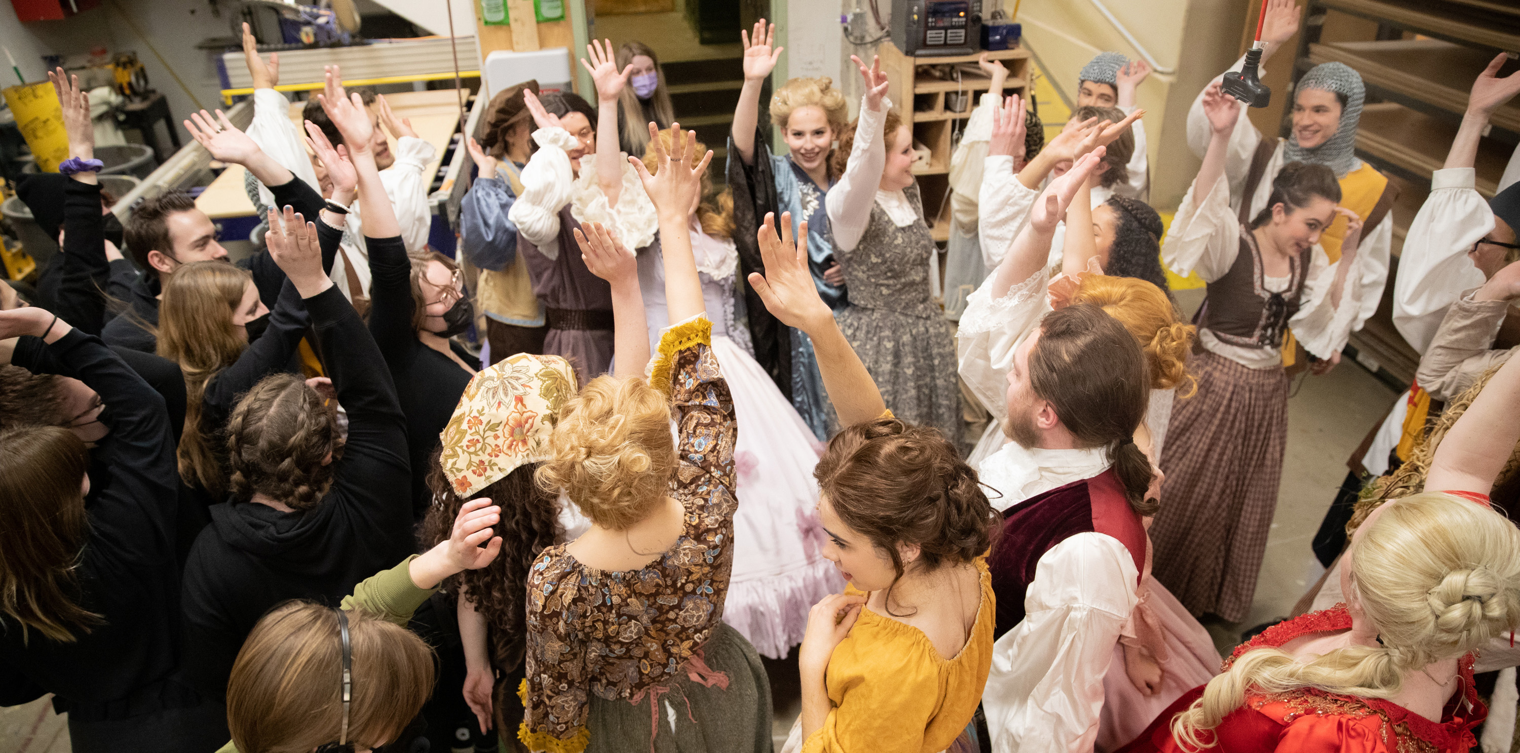 Students in the production of Cinderella raising their hands after a huddle
