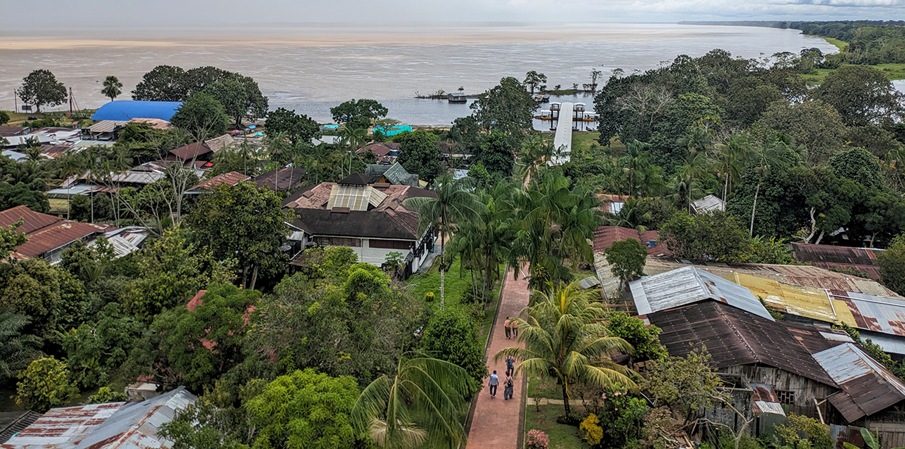 A view of the banks of the Amazon River from a town in Colombia surrounded in green trees.