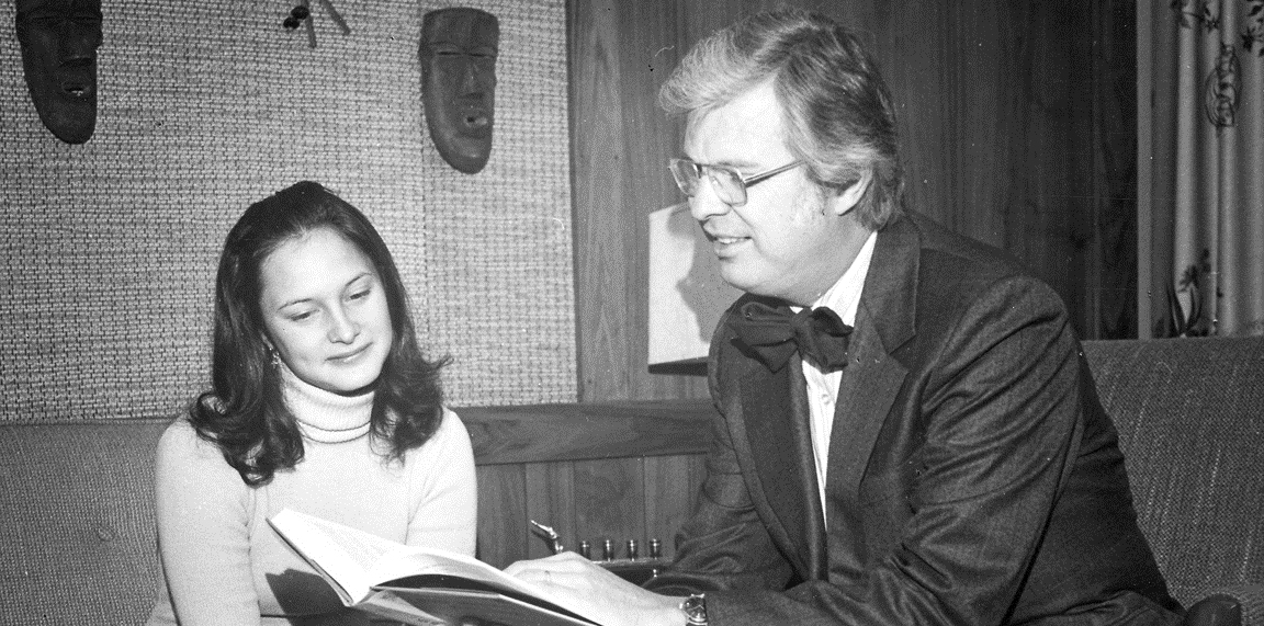 Dick Bond sitting with a female looking at a book