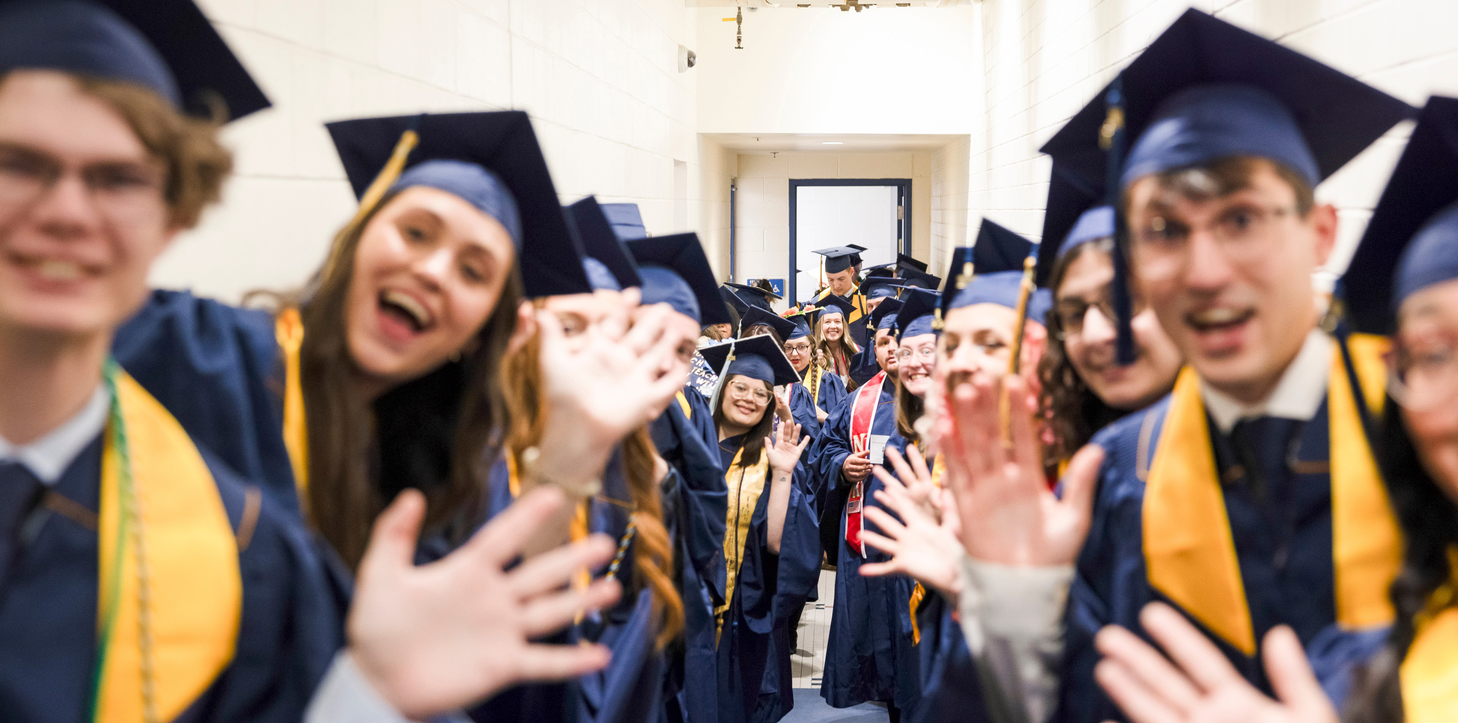 A group of UNC graduates smiling at the camera and waiving