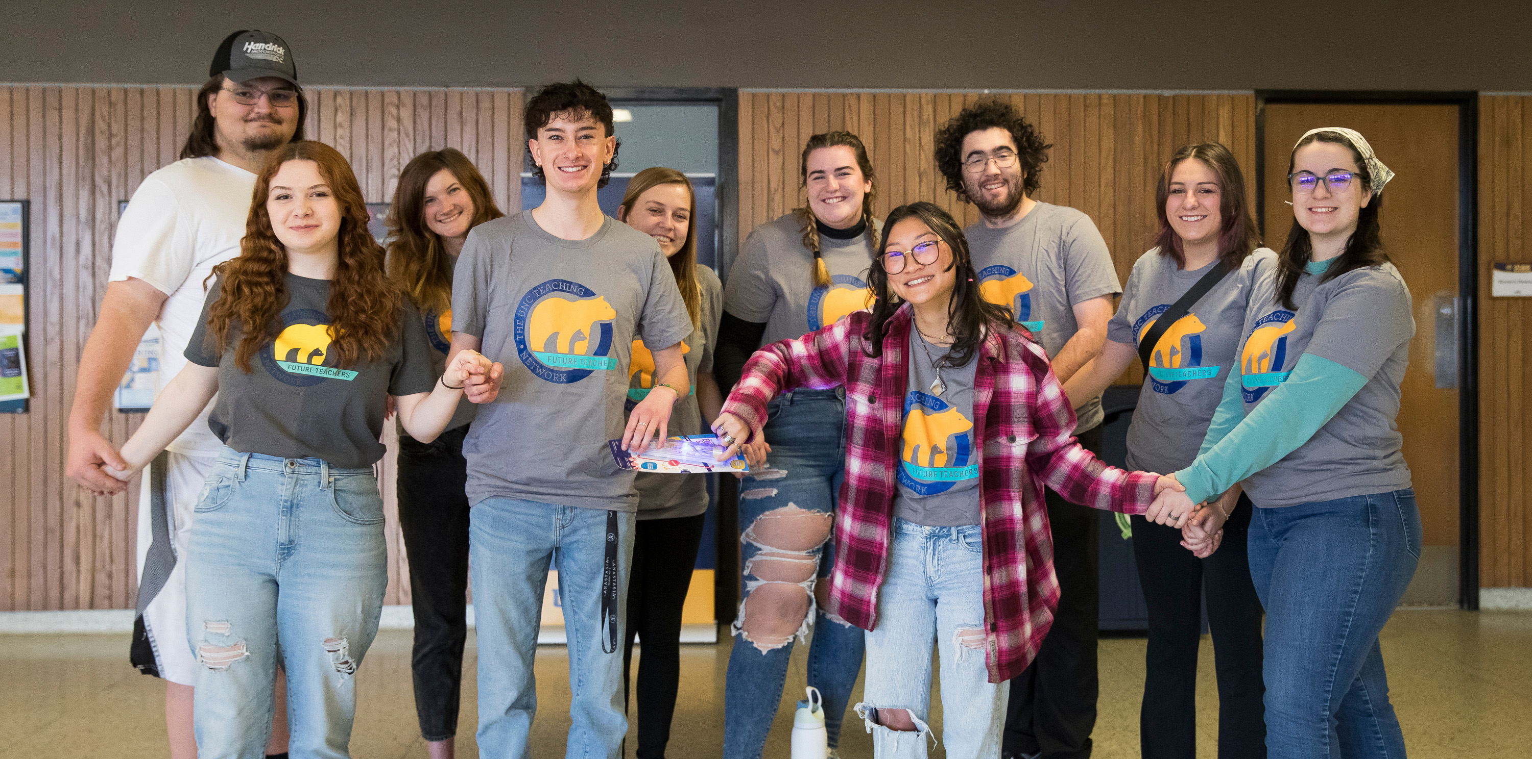 A group of students wearing the same shirt smiling at the camera