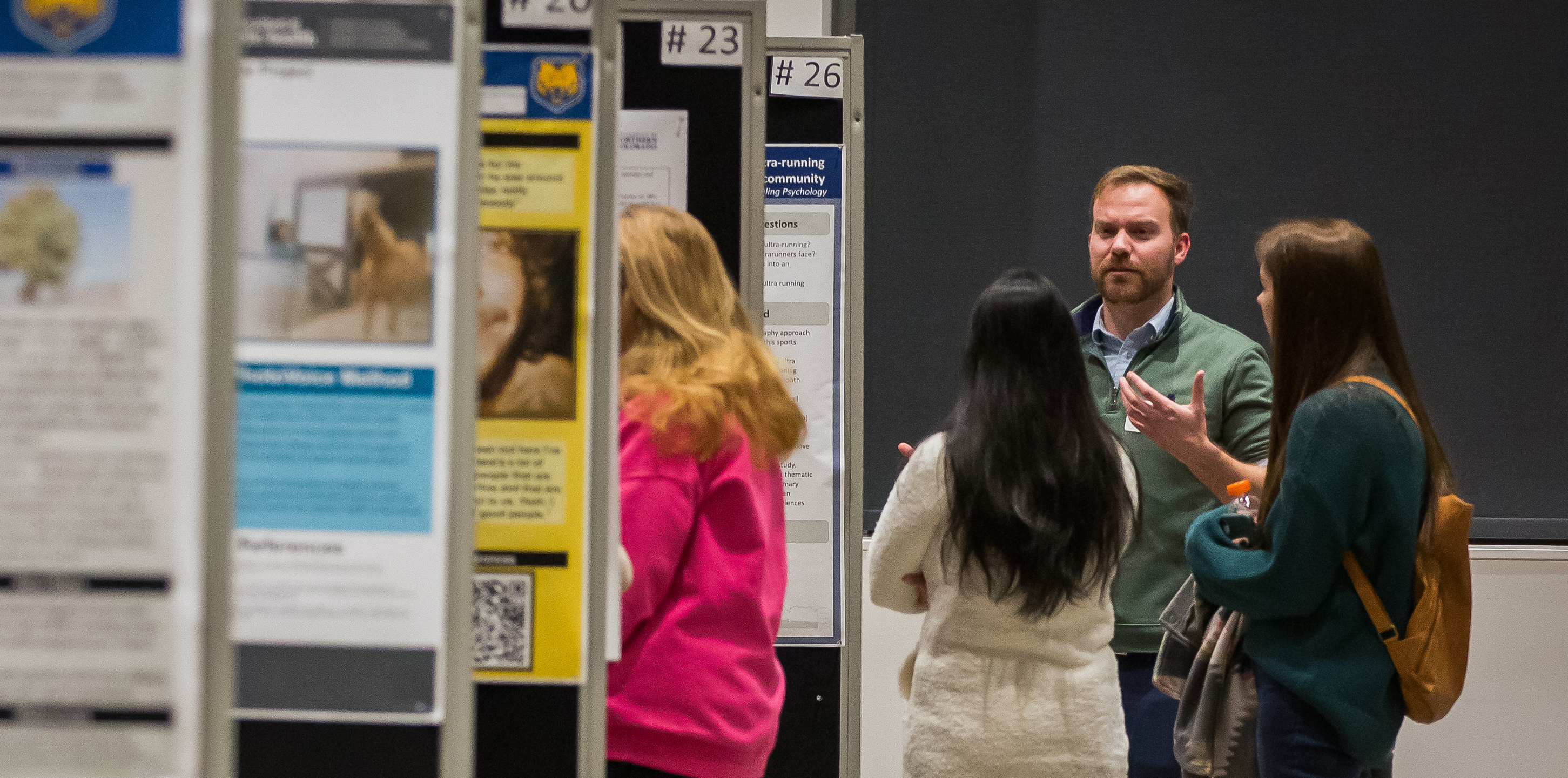 a group of students standing and talking in front of several research posters 