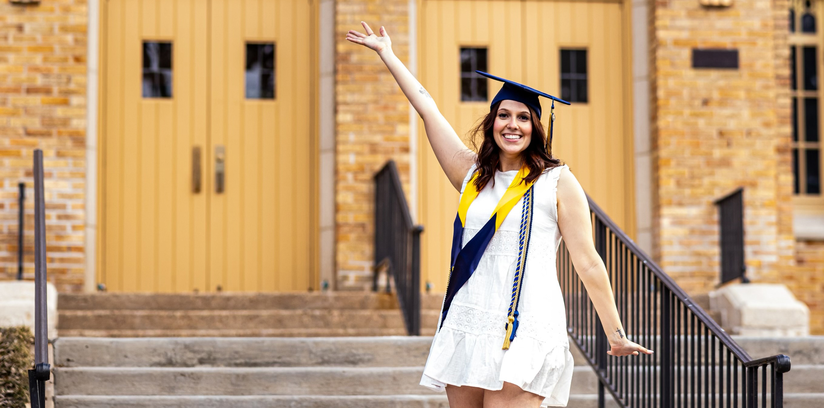 HannahGrace posing with her graduation cap with her arm in the air