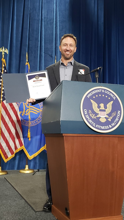 Brian Dauenhauer standing at a podium accepting the PCSFN Hero Award.