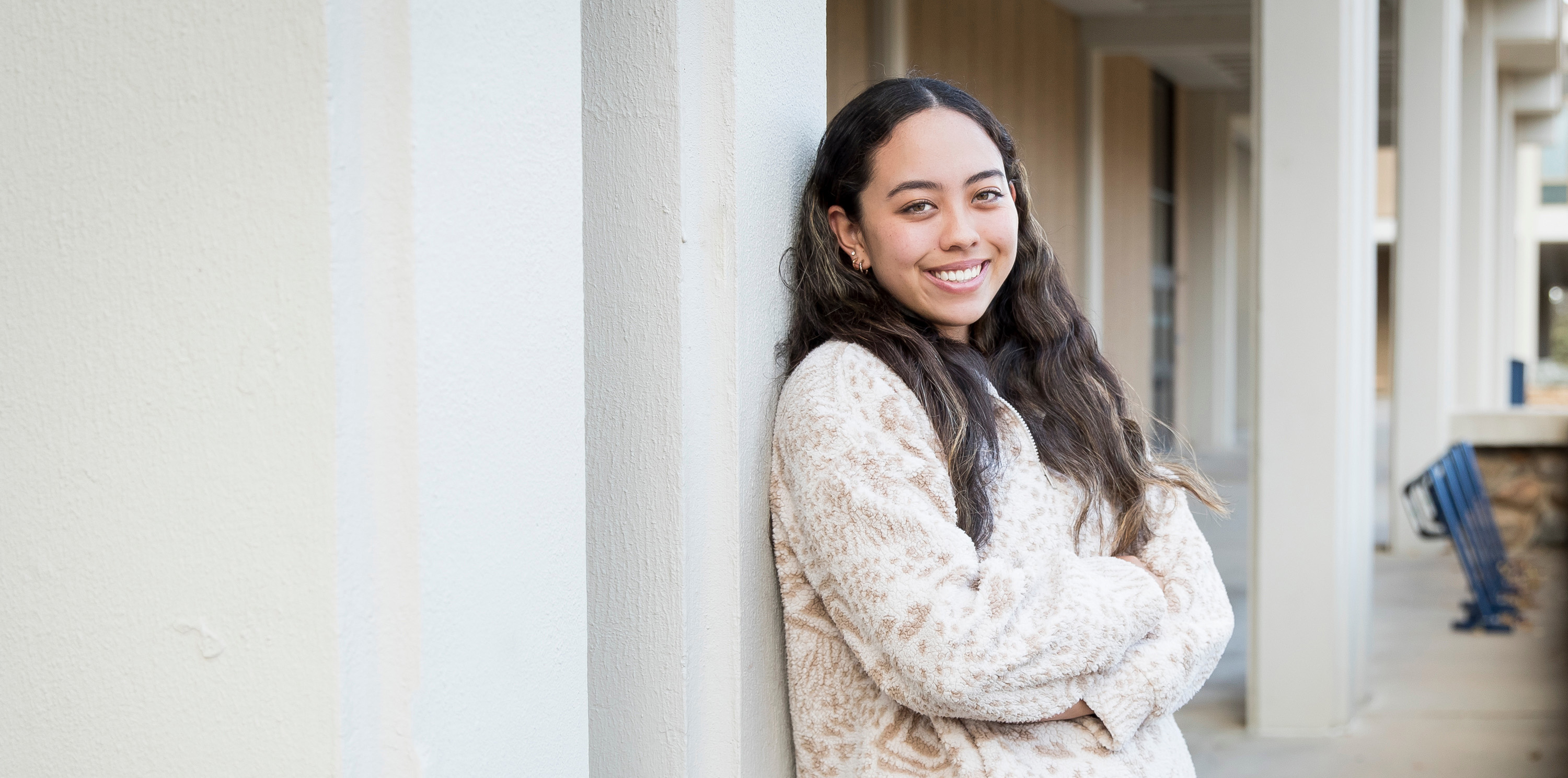 Female student, Shae Lefcourt smiling and leaning on a building on UNC's campus