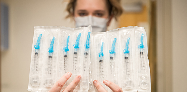 SHC nurse holding packs of vaccine needles