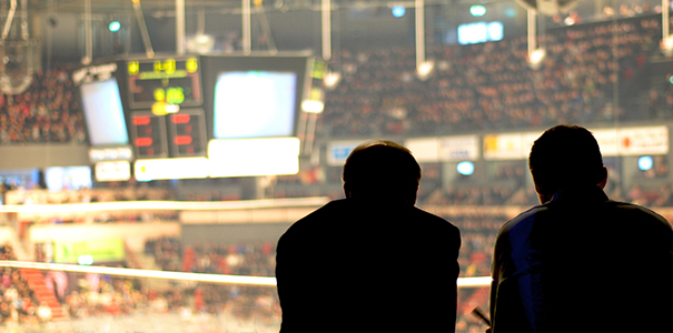 two people in silhouette watching a sporting event at a large arena