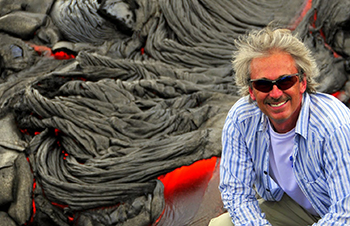 Steve Anderson poses in front of flowing lava.
