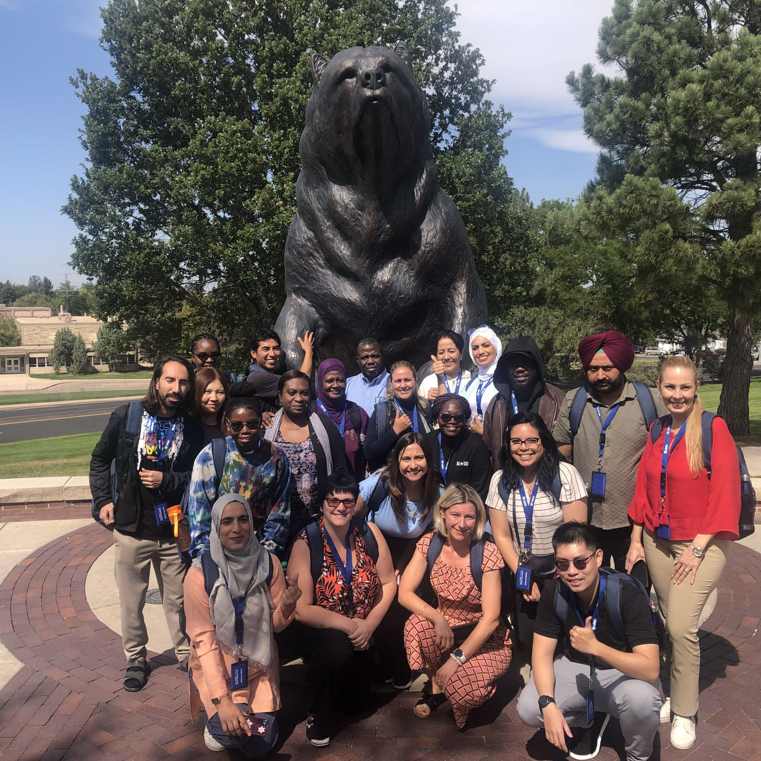 A group of international teachers posing in front of a bear statue