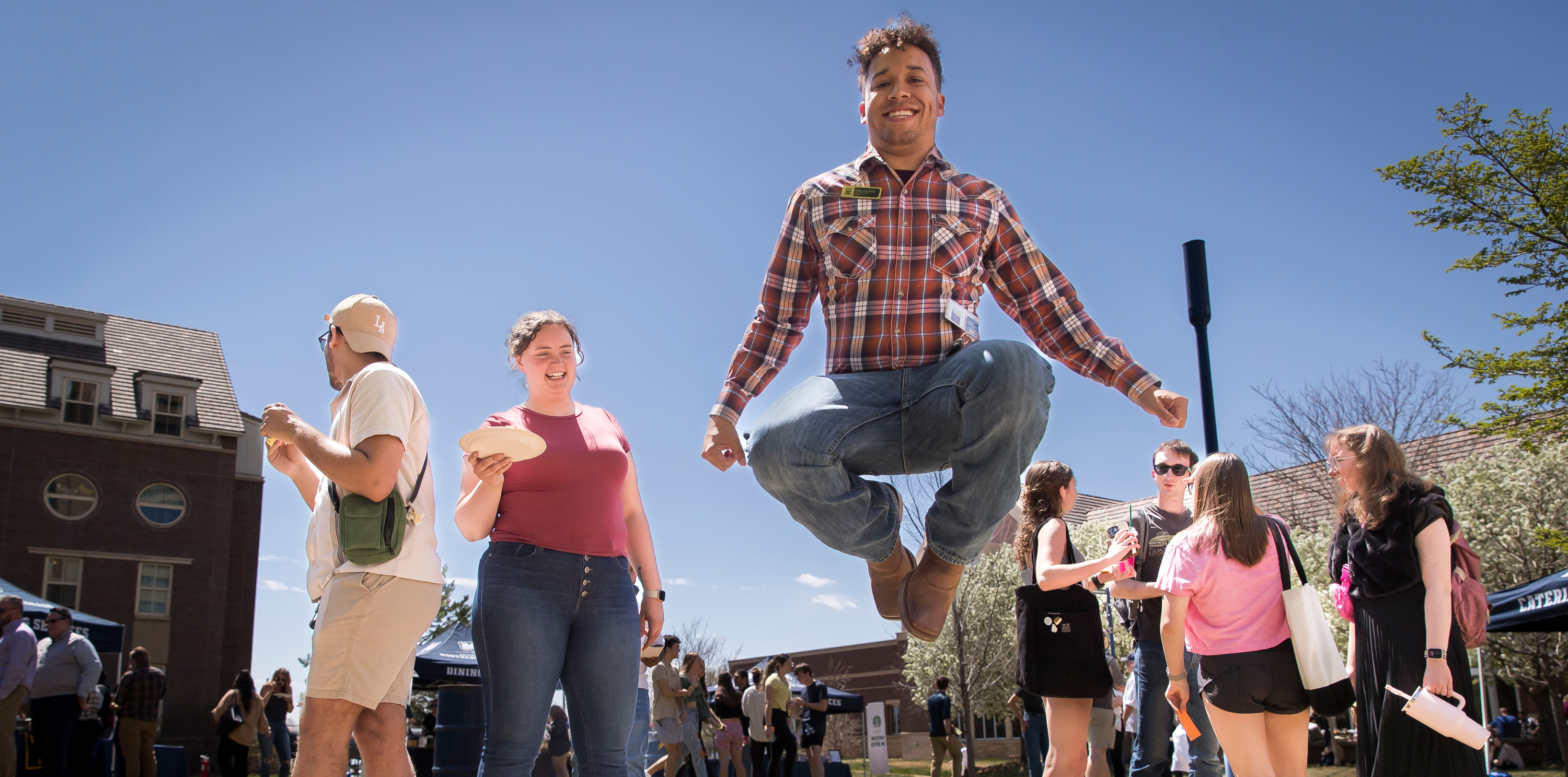 Students standing outside with one jumping in the air with their legs criss crossed