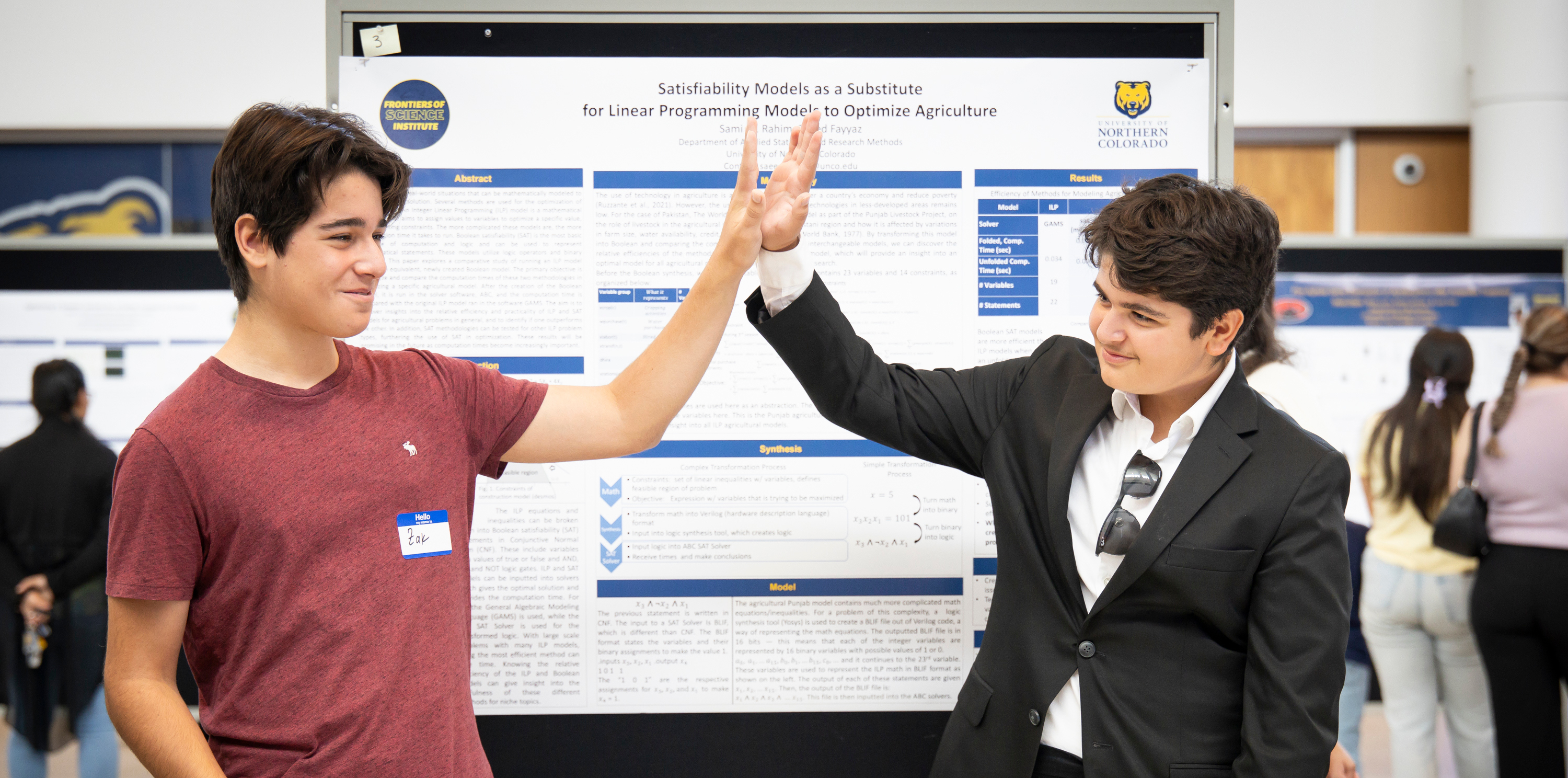 Two research students high fiving in front of a poster