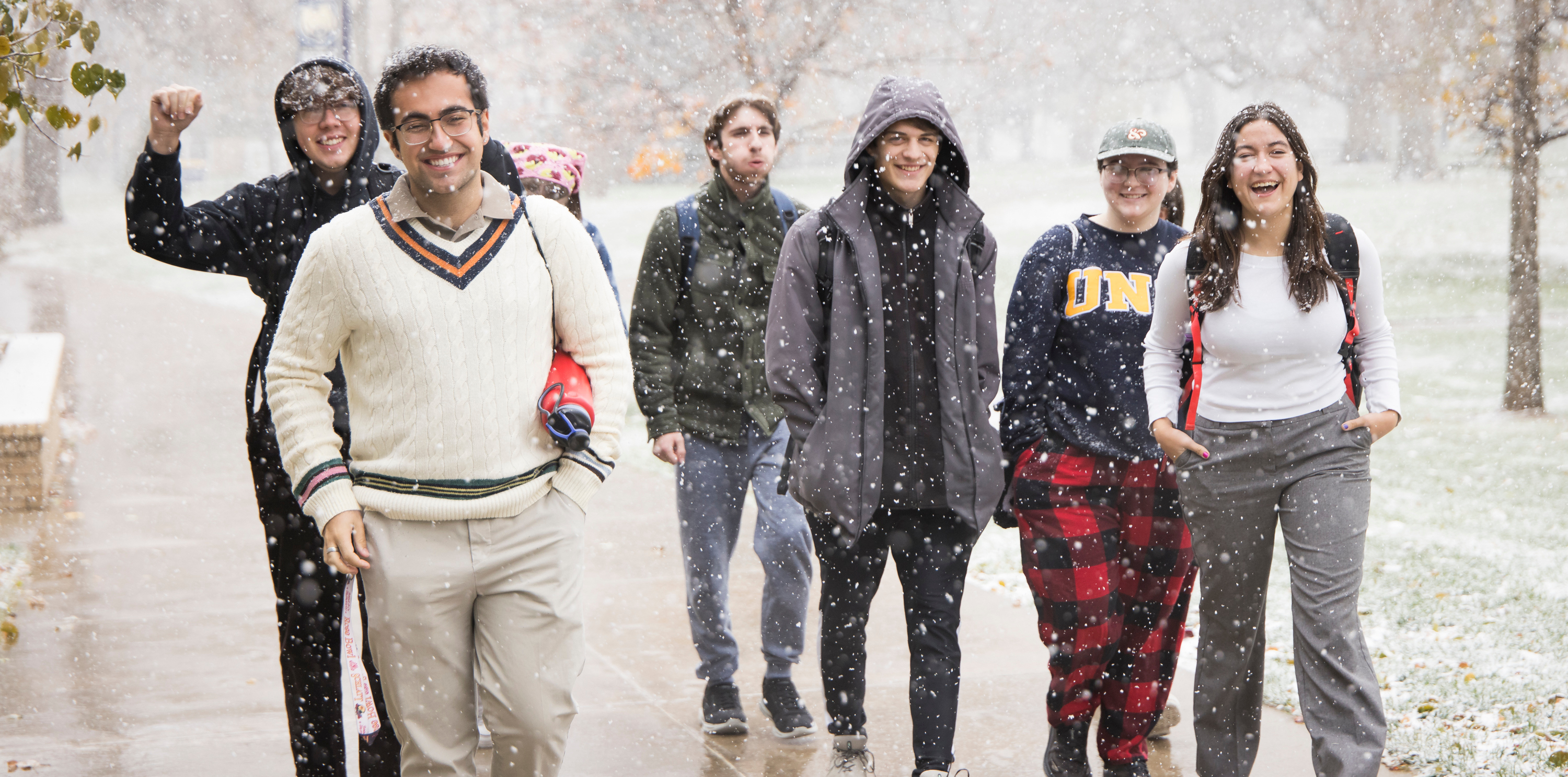 Four students walking on a sidewalk in the snow