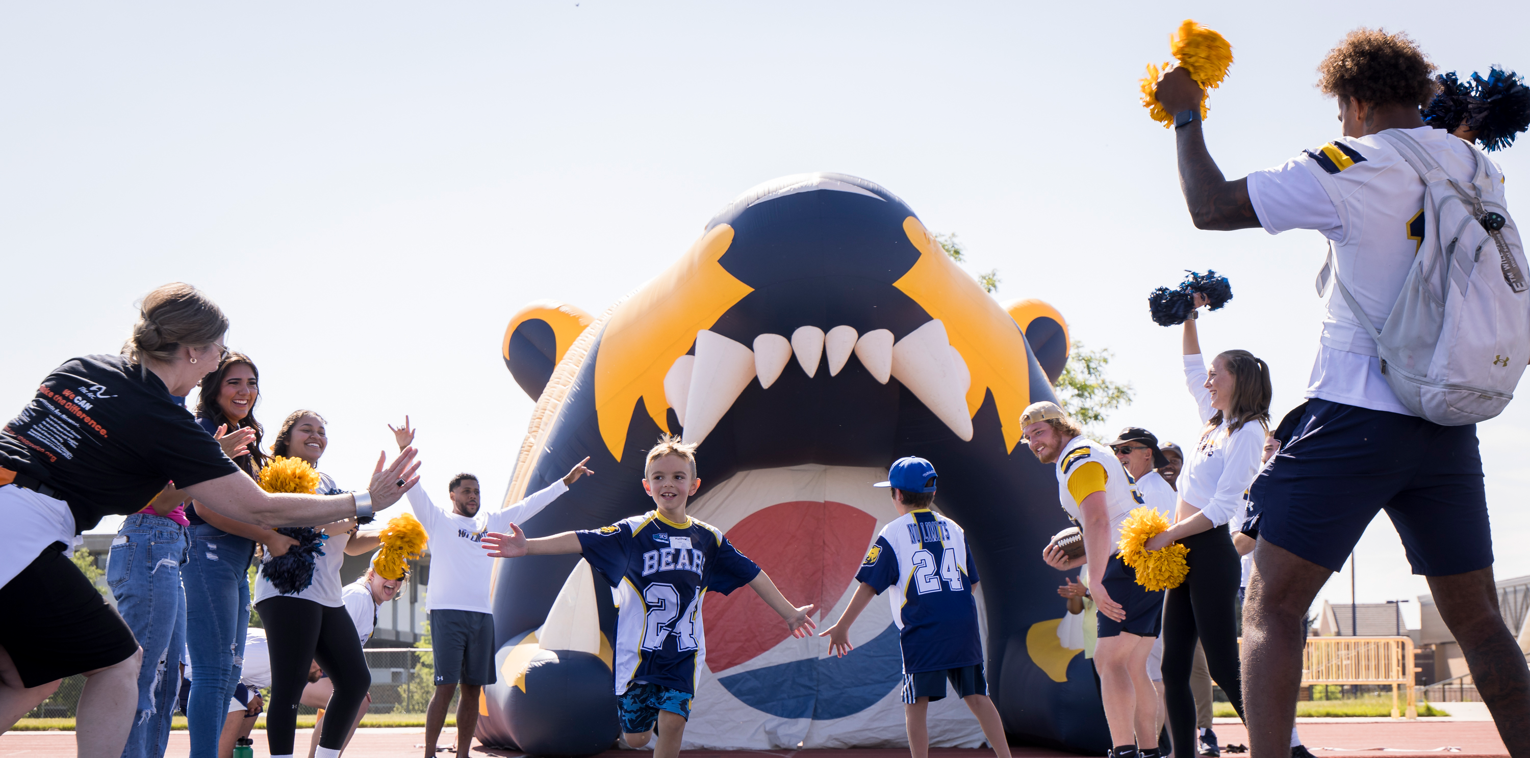 A child running on the football field with people lining on the sides to high five him