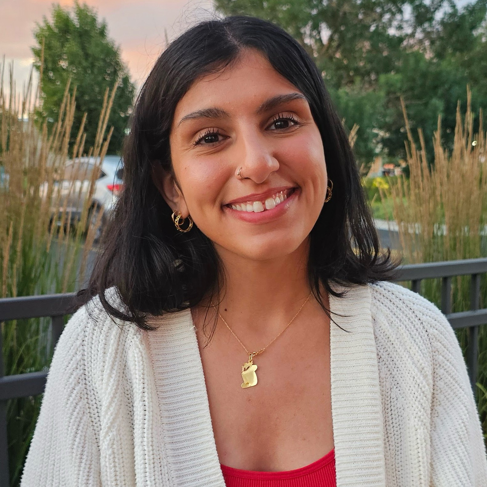 Yasmeen Mustafa smiling outside wearing a red shirt