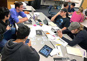 Sam Ptak, UNC Secondary Education Major, works with one of the design teams as they begin their prototype of an original game.