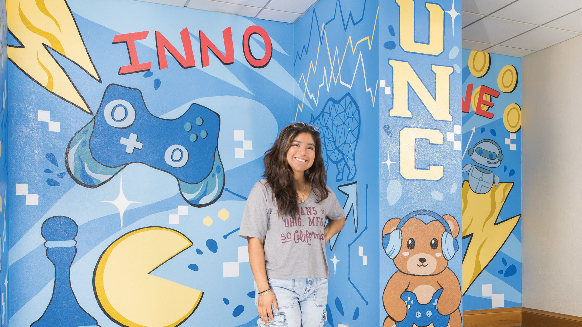 Raquel Eduardo Nunez poses in front of a mural they painted.