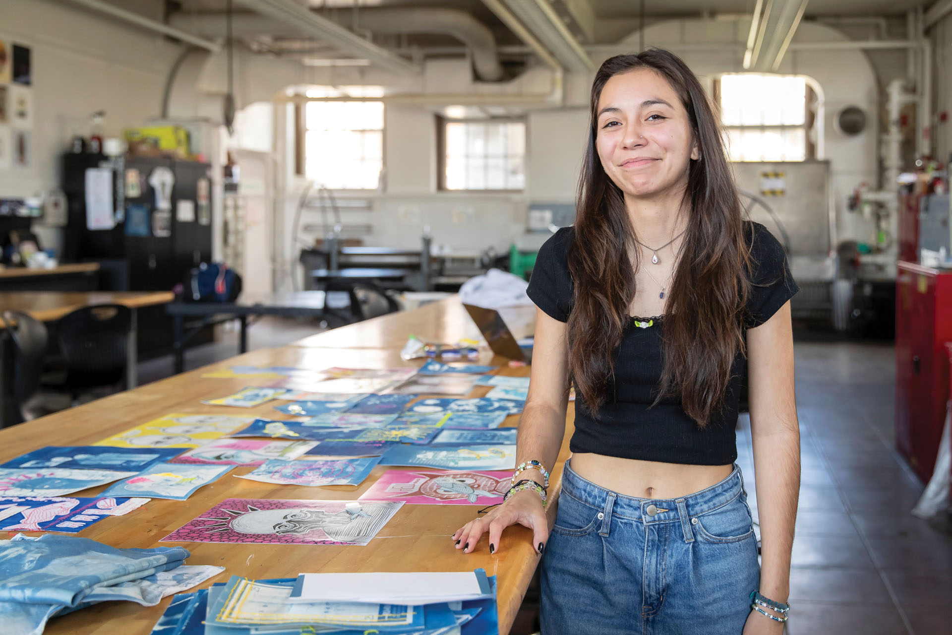 Eva Chavez stands in an art studio surrounded by posters.