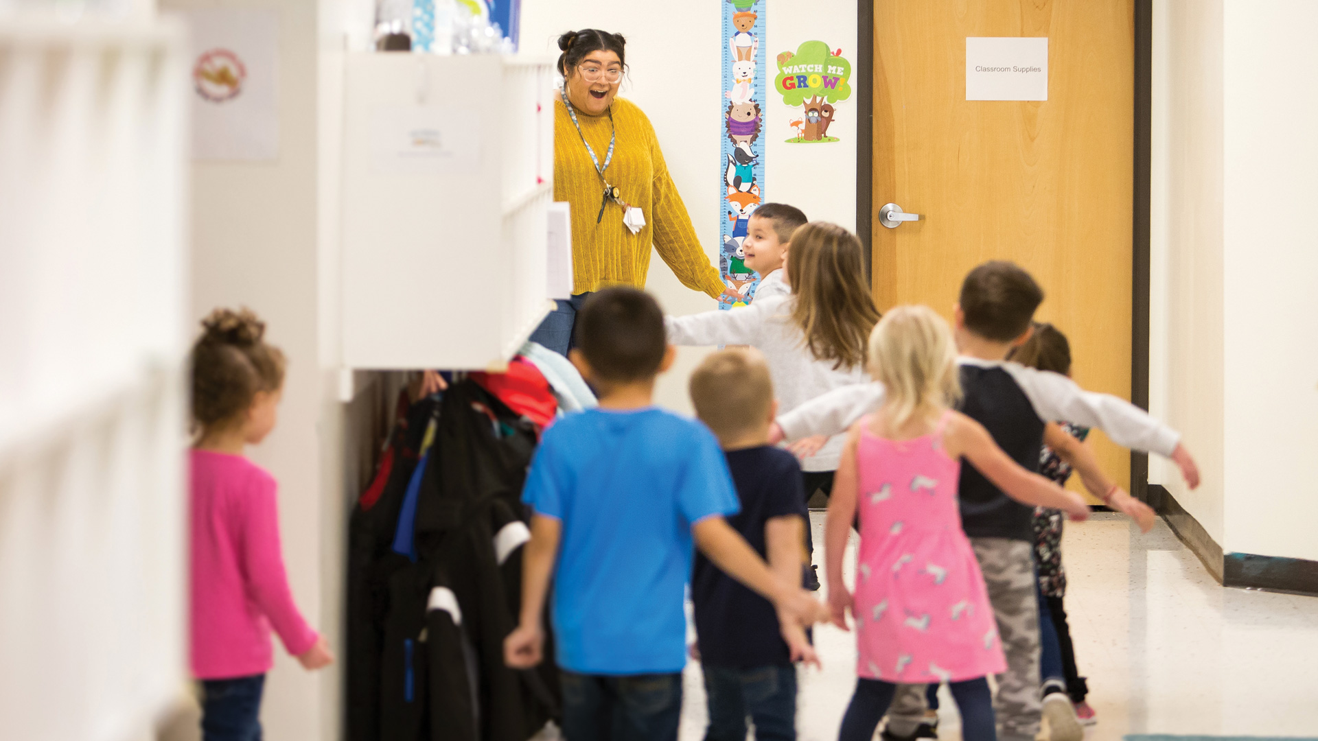 Young students run in the hallway to greet their teacher.