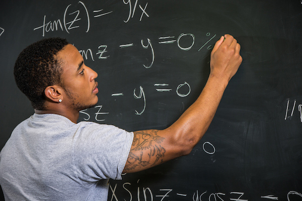 Picture of student writing an equation on chalkboard